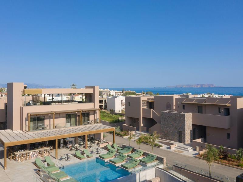 Nowoczesny kompleks hotelowy z basenem, leżakami i widokiem na morze pod czystym niebem.