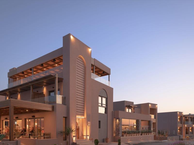 Nowoczesny kompleks hotelowy z ciepłym oświetleniem na zewnątrz o zachodzie słońca.