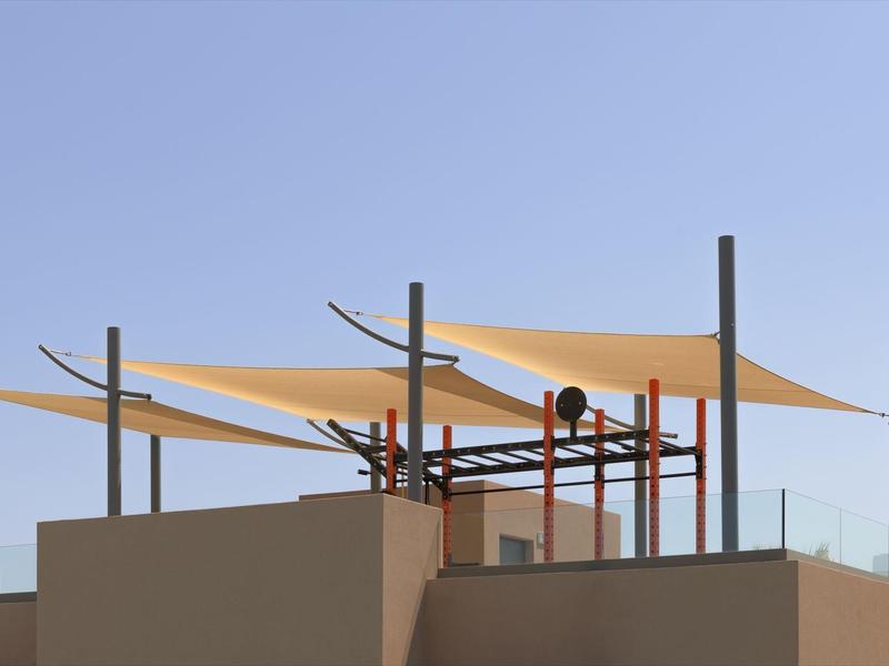 Taras na dachu z nowoczesnymi żaglami przeciwsłonecznymi i jasnym niebieskim niebem w tle.