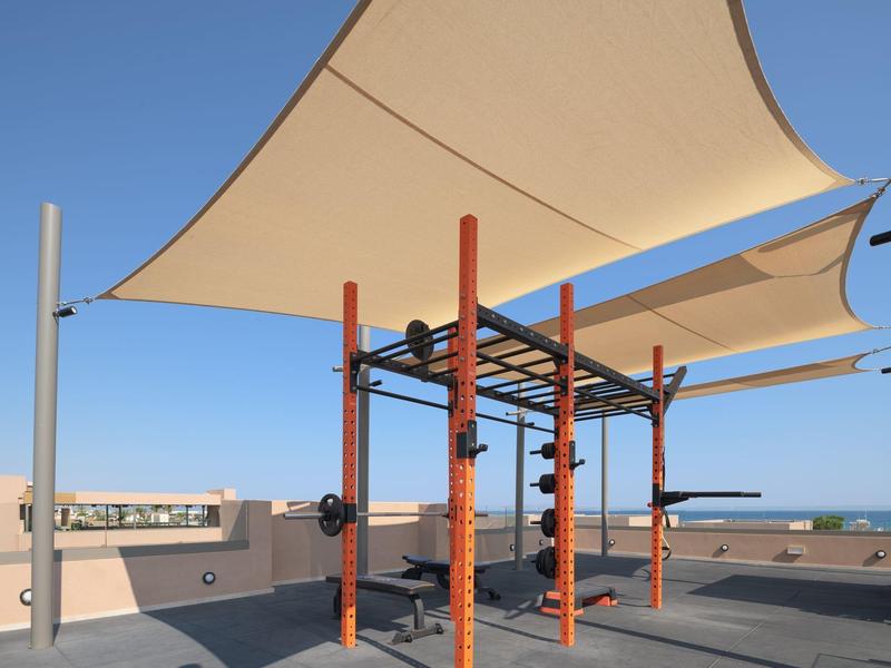 Nowoczesny zewnętrzny plac do ćwiczeń z daszkami przeciwsłonecznymi na dachu przy czystym niebie.