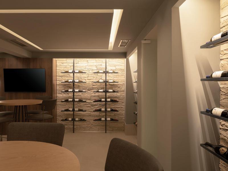 Nowoczesna piwnica win z półkami na wino, przyciemnionym światłem i strefą siedzącą w ciepłych kolorach.