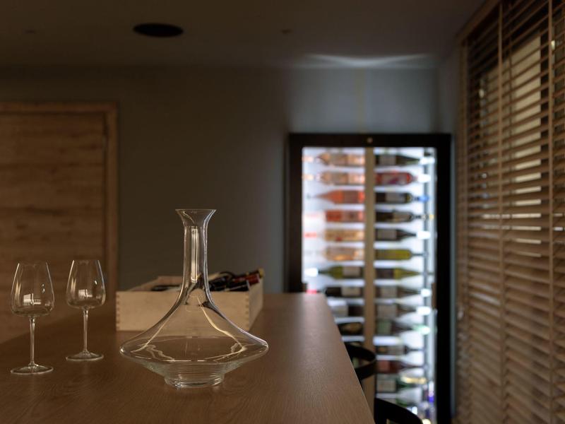 Nowoczesny pokój hotelowy z chłodziarką do wina, karafką i dwoma kieliszkami na drewnianym stole.