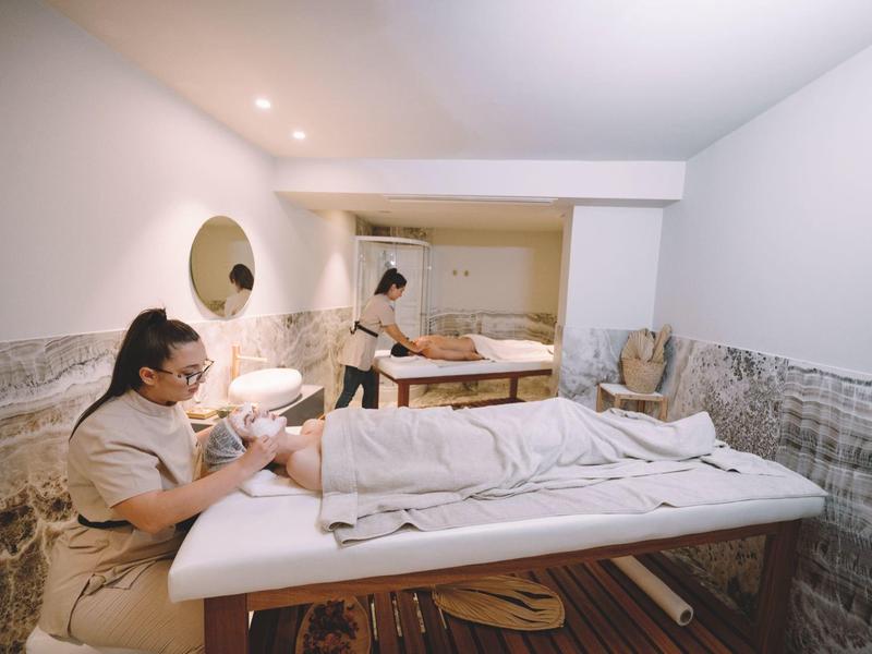 Dwie kobiety w jasnym, spokojnym spa, jedna otrzymuje masaż.