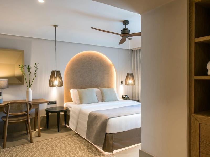 Stylowy pokój hotelowy z łóżkiem podwójnym, biurkiem i pośrednim oświetleniem zagłówka.