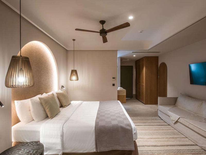 Nowoczesny pokój hotelowy z dużym łóżkiem, sofą i ciepłym oświetleniem.