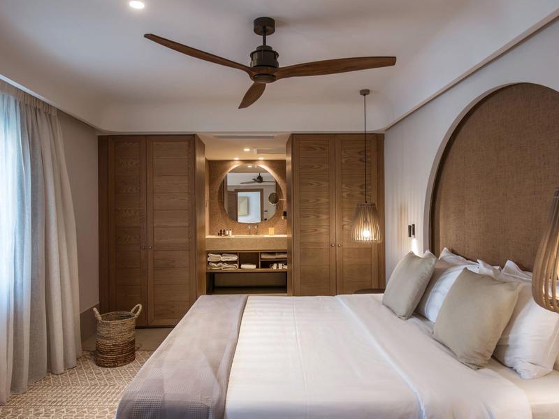 Elegancki pokój hotelowy z dużym łóżkiem, wentylatorem sufitowym i łazienką.