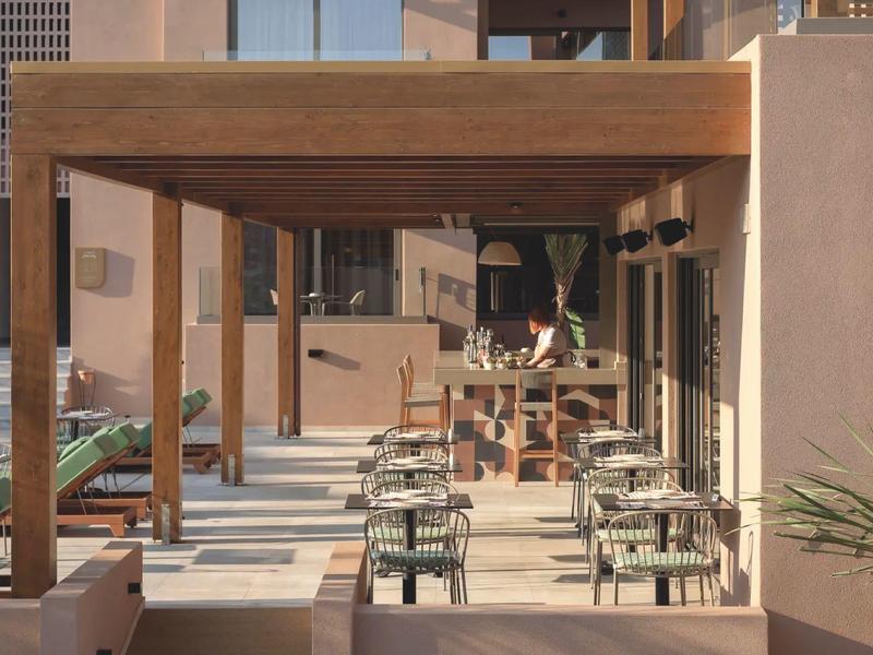 Nowoczesna przestrzeń na zewnątrz z stołami i krzesłami pod drewnianym pergolą.