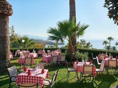 Ristorante all'aperto con tovaglie a quadri rosse e bianche e vista sul mare