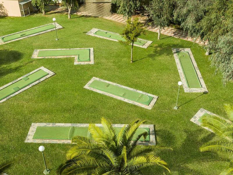 Jardin verdoyant avec plusieurs parcours de mini-golf dans une station hôtelière.