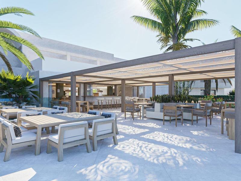 Espace extérieur moderne d'hôtel avec sièges couverts et plantes tropicales.