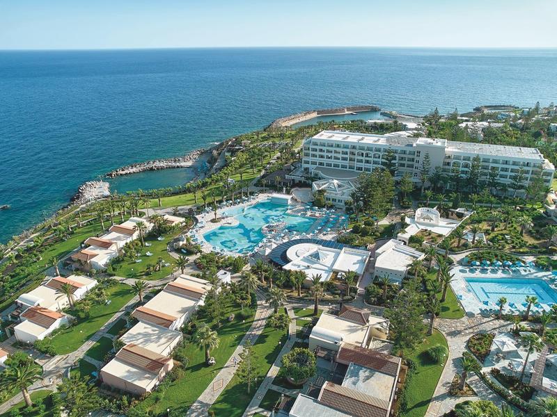 Vue aérienne d'une station balnéaire de luxe avec plusieurs piscines et villas au bord de la mer.