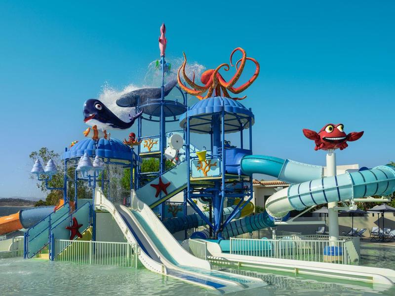 Parc aquatique coloré avec toboggans et décorations de créatures marines sous un ciel bleu