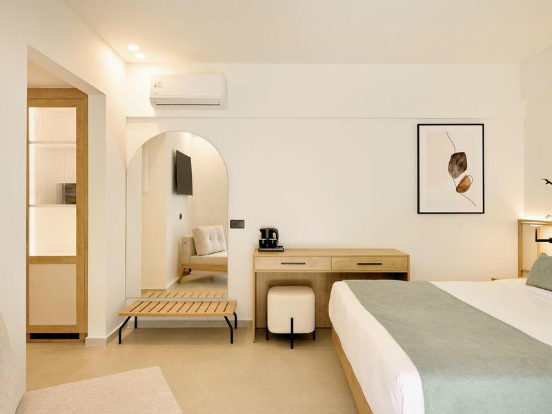 Chambre d'hôtel moderne avec lit double, bureau, banc et décoration minimaliste.