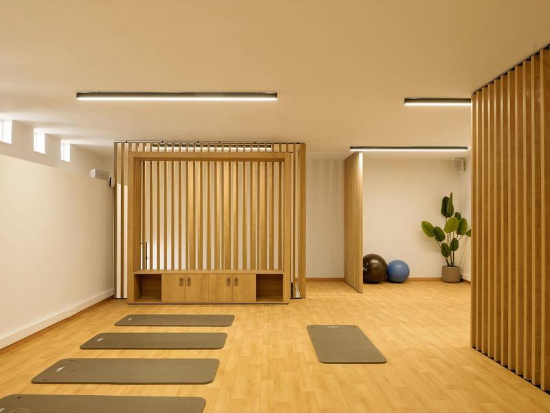Salle de yoga moderne et minimaliste avec sol en bois, tapis et ballons de fitness.
