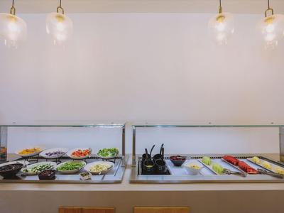 Bufet z świeżymi sałatkami, sosami i warzywami w nowoczesnej restauracji hotelowej.