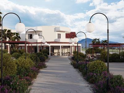 Bestraat pad met straatlantaarns leidt naar wit gebouw met rode daken en palmbomen.