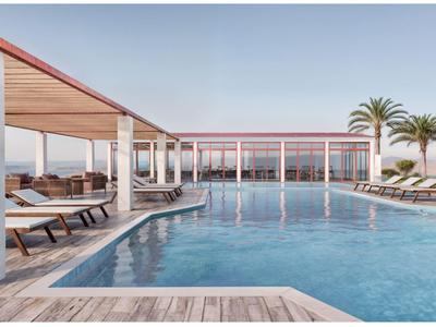 Moderne buitenzwembad met ligstoelen en palmbomen op een zonnige dag.