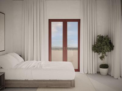 Schlafzimmer mit weißem Bett, großen Vorhängen und Türen mit Meerblick.