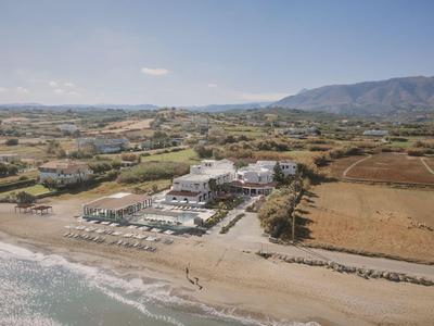 Hotelcomplex met zwembad nabij een zandstrand en bergen op de achtergrond