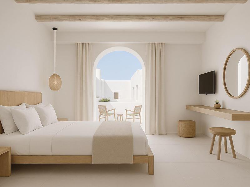 Hell eingerichtetes Schlafzimmer mit Bett, Hocker, Spiegel und Blick auf Balkon und Meer.