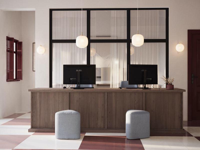 Moderner Empfangsbereich mit Holzschalter, zwei Computern und zwei grauen Hockern.