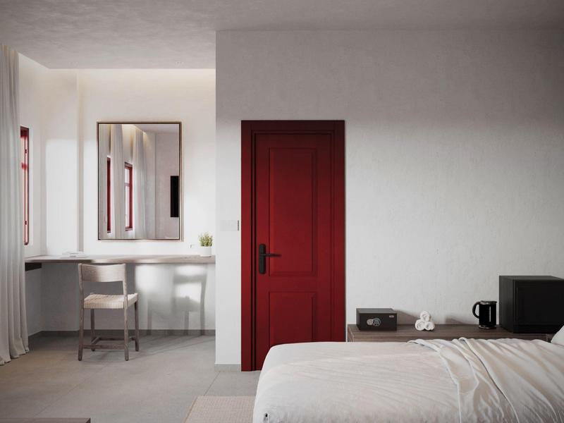 Modernes Hotelzimmer mit roter Tür, Schreibtisch, Stuhl, Bett und Minibar.