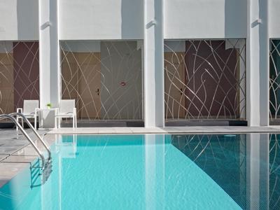 Nowoczesny basen na zewnątrz z czystą niebieską wodą i dekoracyjnymi panelami ściennymi.