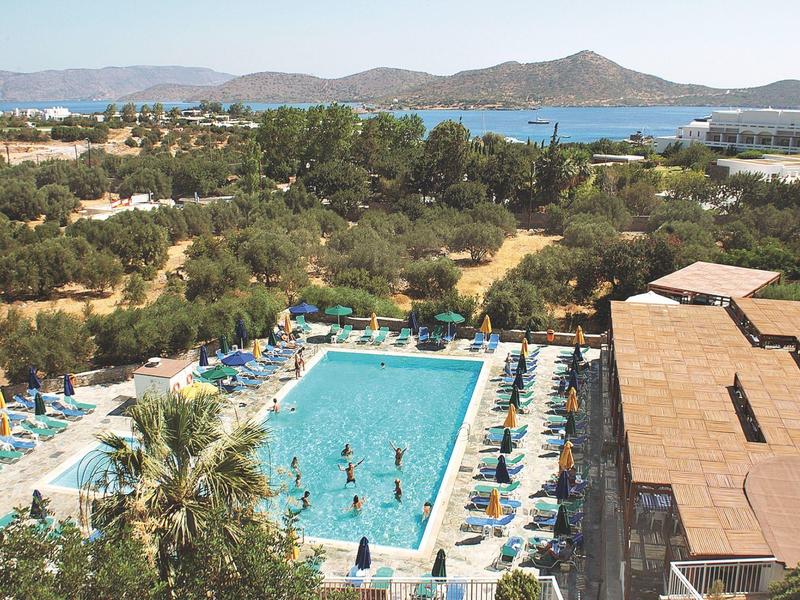 Vista de una piscina rectangular con tumbonas y montañas al fondo.
