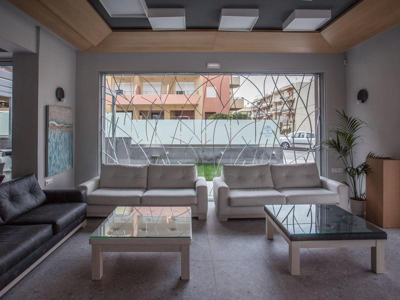 Área de lounge moderna de hotel con grandes sofás y mesas de café de vidrio junto a una gran ventana.