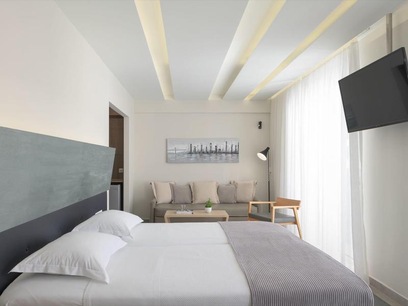 Habitación de hotel moderna con cama doble, sofá, cuadro y televisor colgado