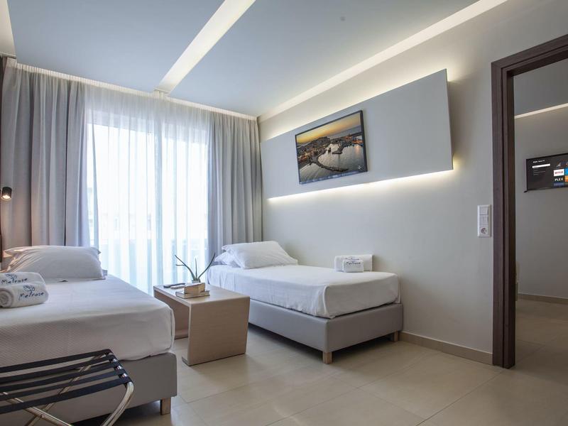 Habitación de hotel moderna con dos camas individuales, ventana grande y diseño minimalista.