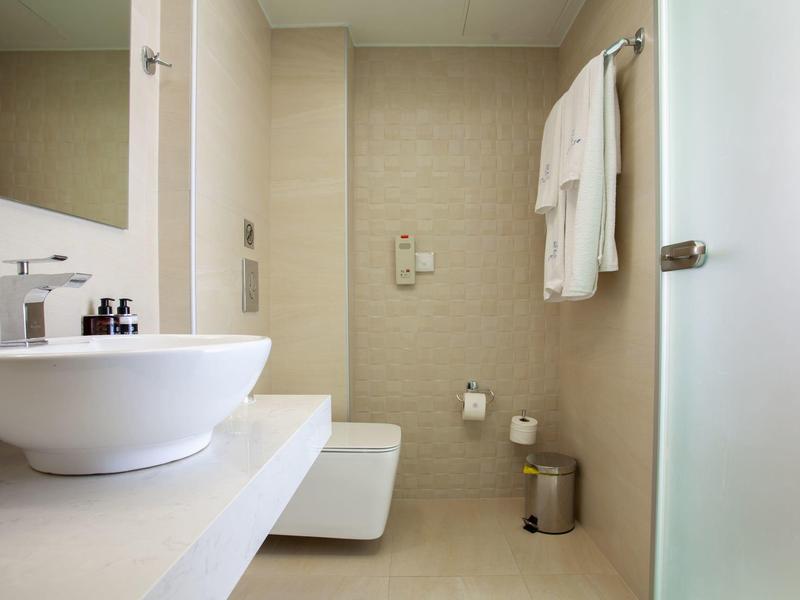 Baño moderno con lavabo, toallero e inodoro en tonos neutros.