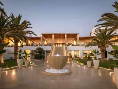 Luxuriöses Hotel mit Pool, Palmen und moderner Architektur in warmem Abendlicht.