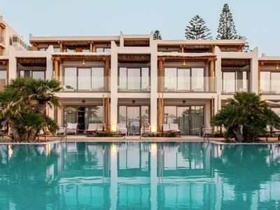 Modernes mehrstöckiges Hotel mit großen Glasfenstern und Palmen neben dem klaren Swimmingpool.