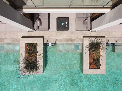 Dachterrasse mit zwei Begrenzungsbeeten und türkisfarbenem Wasserbecken darunter.