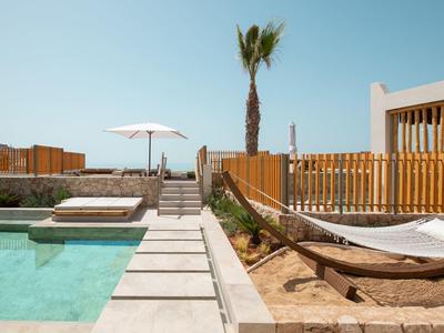 Moderner Pool mit klar blauem Wasser, Liegestuhl, Sonnenschirm und Palme bei klarem Himmel.
