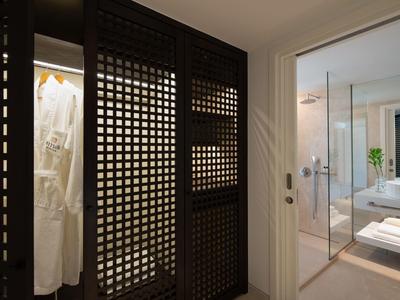 Camera d'hotel moderna con cabina armadio e bagno aperto con parete in vetro.