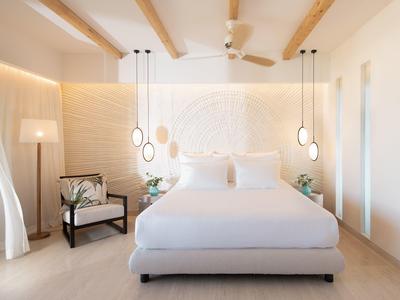 Camera luminosa e moderna con letto comodo, lampade sospese e travi in legno sul soffitto.