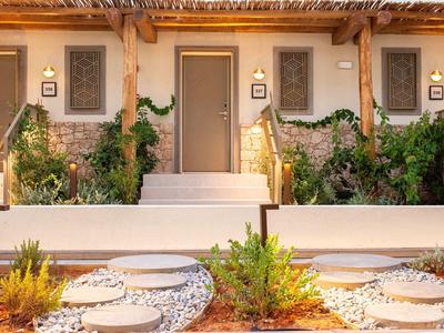 Ingresso delle camere d'hotel con scale, piante e luci calde al tramonto.