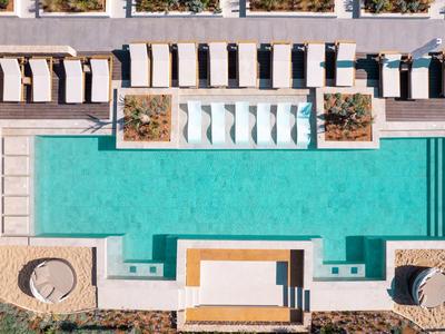 Letecký pohled na obdélníkový bazén s lehátky a zastíněnými oblastmi.