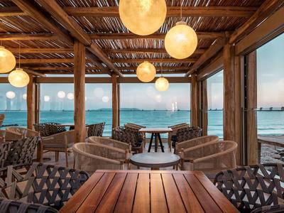 Příjemný plážový bar s dřevěným stropem a západem slunce nad mořem.