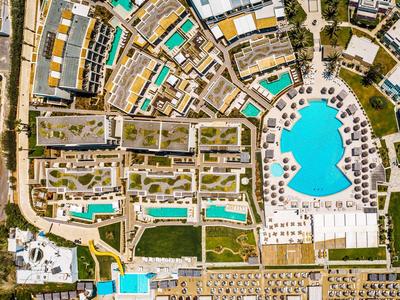Vista aerea di un resort con più piscine, spiagge e edifici disposti in modo organico.