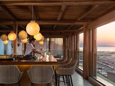 Bar con sgabelli e grandi finestre con vista sul mare al tramonto