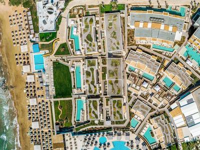 Vista aerea di un resort con piscine, edifici e il mare adiacente
