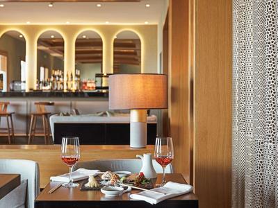 Un accogliente zona ristorante con tavolo apparecchiato, bicchieri di vino e un bar sullo sfondo.