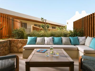 Accogliente terrazza con area salotto, cuscini e tavolo con bevande e riviste.