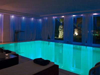 Piscina interna con acqua turchese e illuminazione LED ambientale in una spa dell'hotel.