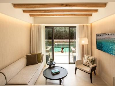 Soggiorno moderno con divano, poltrona, tavolino e vista sulla piscina.