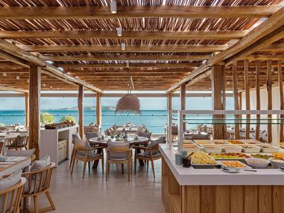 Ristorante aperto in legno con vista mare e tavoli apparecchiati in un hotel.