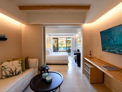 Camera d'hotel moderna con divano, tavolo e vista sulla camera da letto con terrazza.